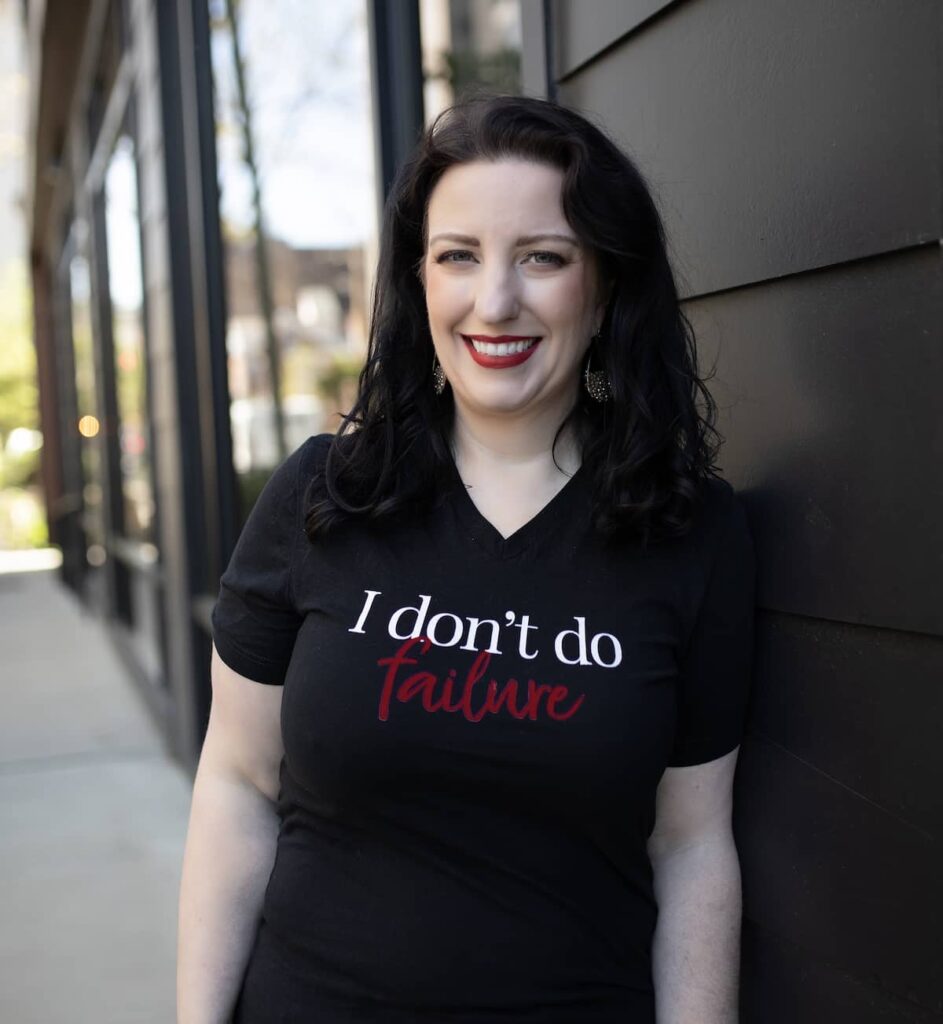 white woman standing outside in a black tshirt that says "i don't do failure".
