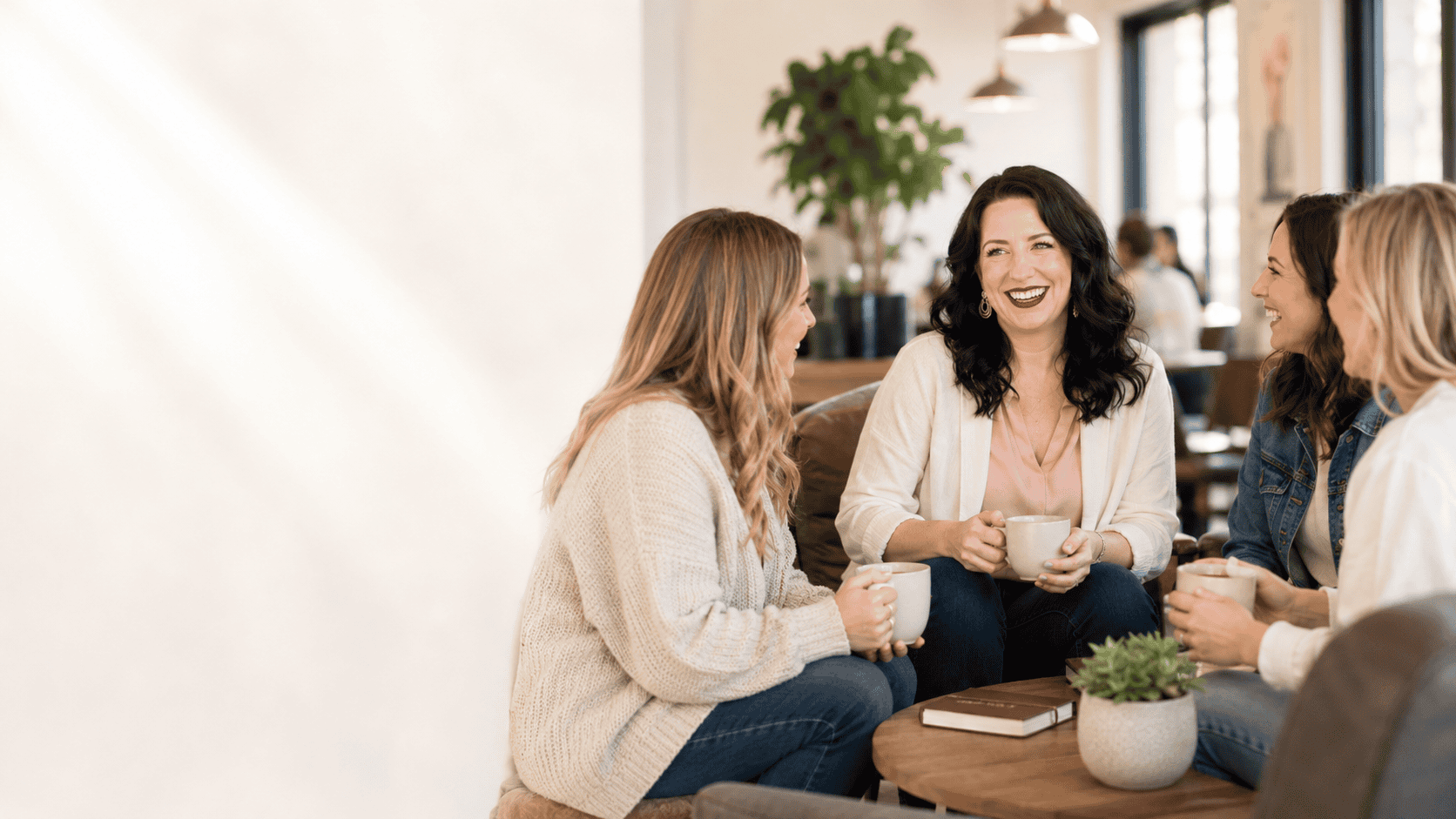 Monica Froese sitting with a group of digital product creators, coffee in hand, laughing together